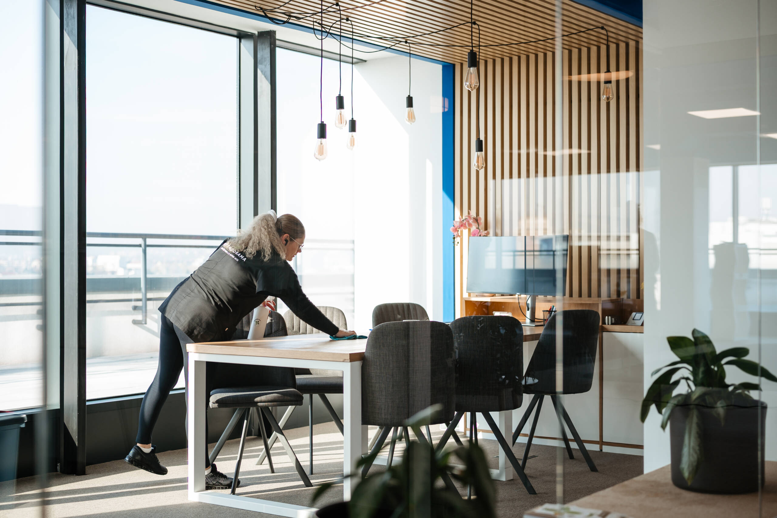 femeie din echipa splendorama, care sterge praful si face curatenie generala intr-o sala de sedinte de birou in Cluj Napoca